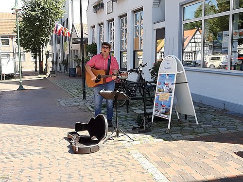 Henning Gumann spielt auf seiner Gitarre bei strahlendem Sonnenschein vor der Touristinfo